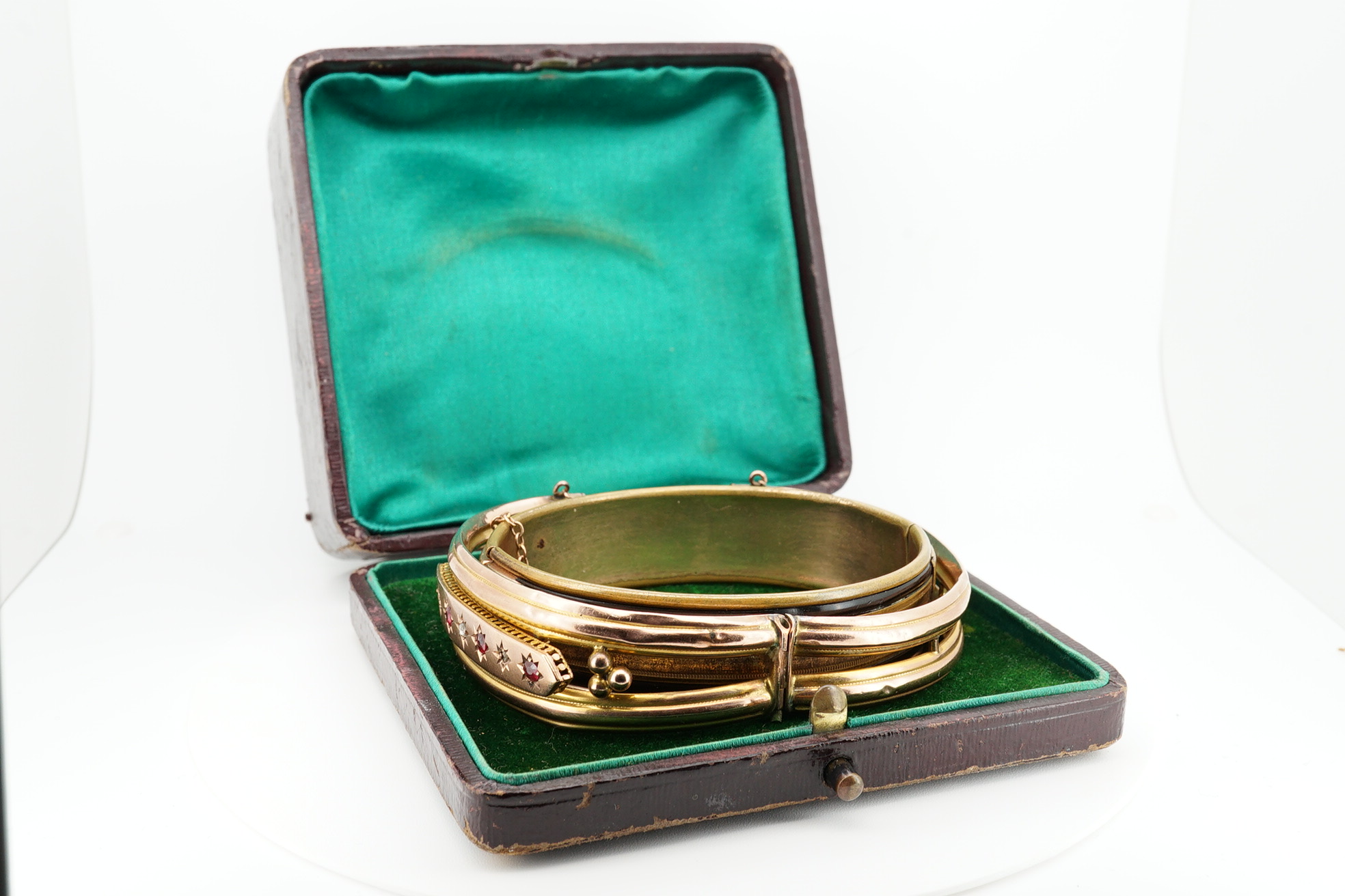 An Edwardian 9ct gold, and gypsy set ruby and diamond set hinged bangle, gross 11.4 grams, together with a gilt metal hinged bangle. Condition - poor.